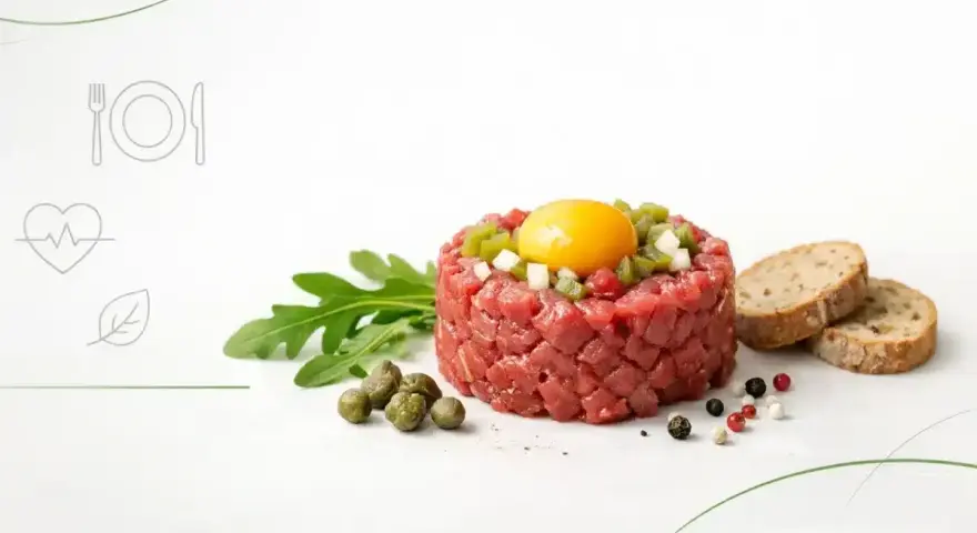 Tatar z surowego mięsa z żółtkiem i dodatkami, obok pieczywo. Czy tatar jest zdrowy? Zależy od składników i sposobu przygotowania.
