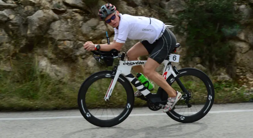 Zawodnik na rowerze triathlonowym pokonuje długi Ironman dystans, pędząc po górskiej trasie.