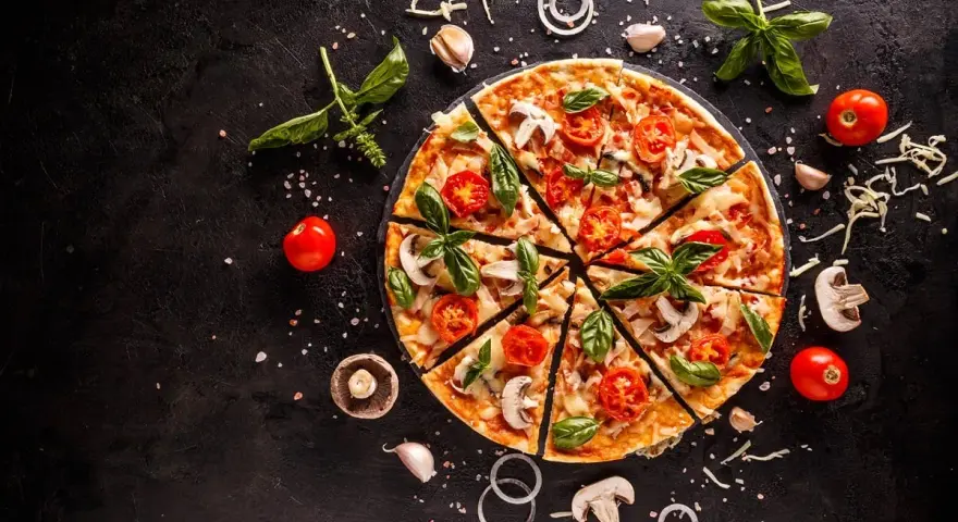 Pyszna pizza z pomidorkami, pieczarkami i bazylią. Zastanawiasz się, ile kcal ma pizza? To zależy od składników!