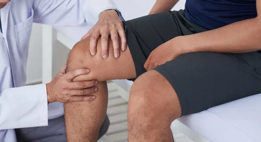 Fizjoterapeuta bada kolano pacjenta, sugerując ćwiczenia na chondromalację rzepki.