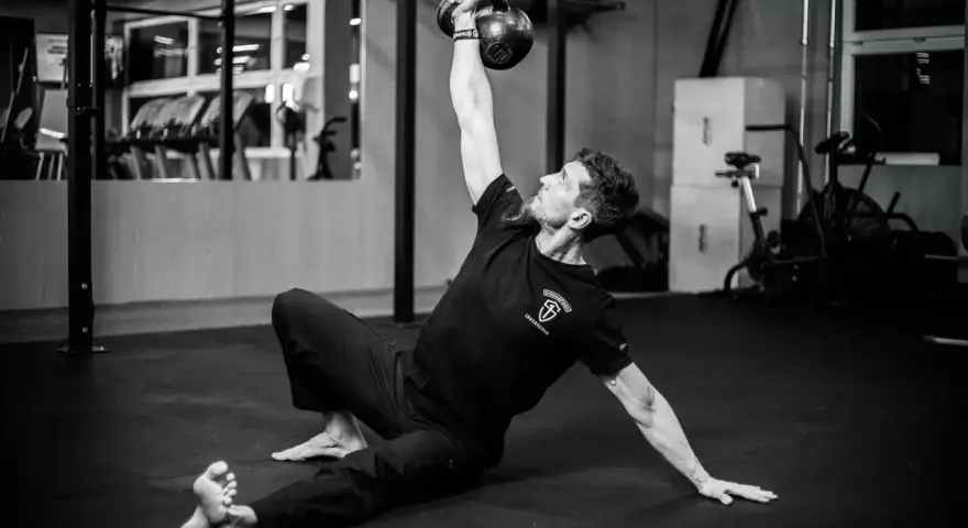 Mężczyzna wykonuje ćwiczenia na siłowni z kettlebell.