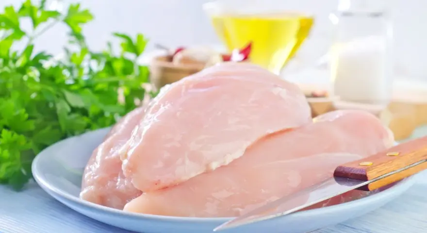 Surowe filety z kurczaka na talerzu, gotowe do przygotowania. W tle olej, sól i natka pietruszki. Idealne dla dbających o filet z kurczaka kcal.
