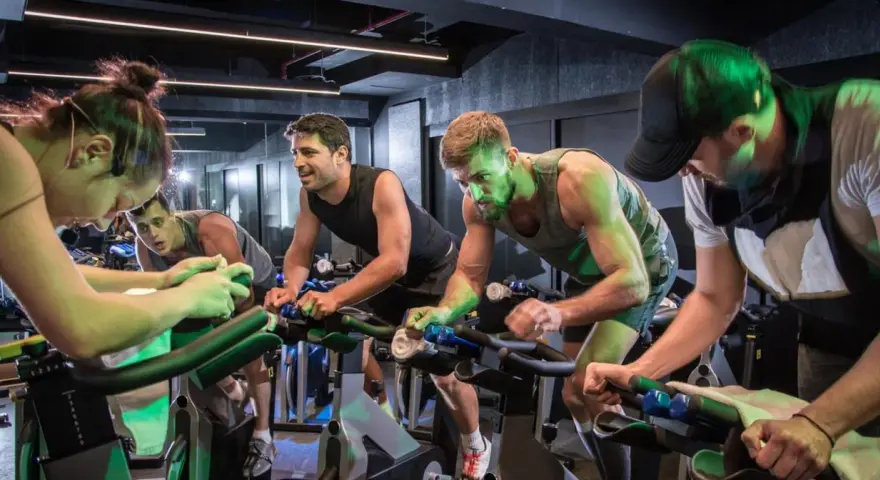 Intensywny trening spinningowy w grupie. Ludzie z determinacją kręcą pedałami, każdy w swoim rytmie.