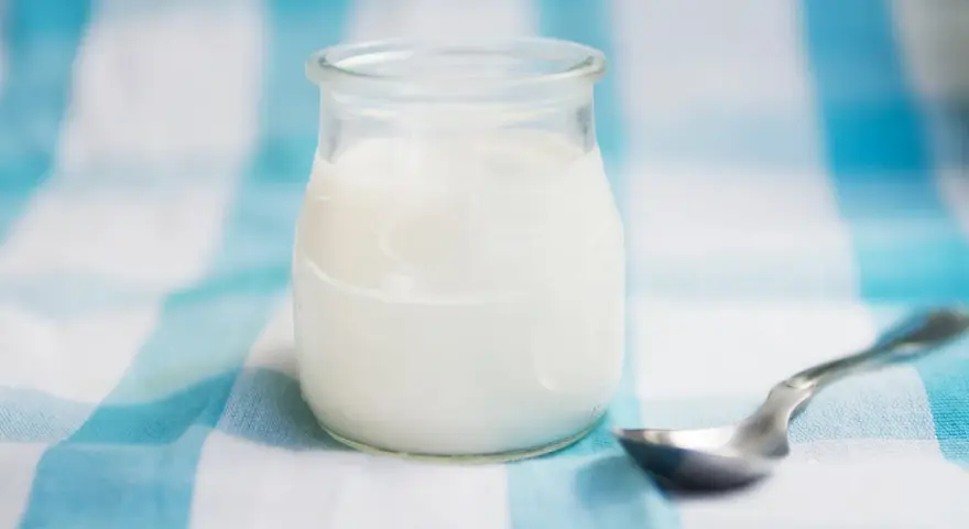 Słoiczek z domowym jogurtem, pełnym naturalnych probiotyków, czeka na łyżeczkę.