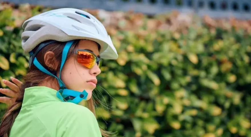 Młoda rowerzystka w kasku i okularach przeciwsłonecznych. Czy kask na rower jest obowiązkowy? Bezpieczeństwo przede wszystkim!