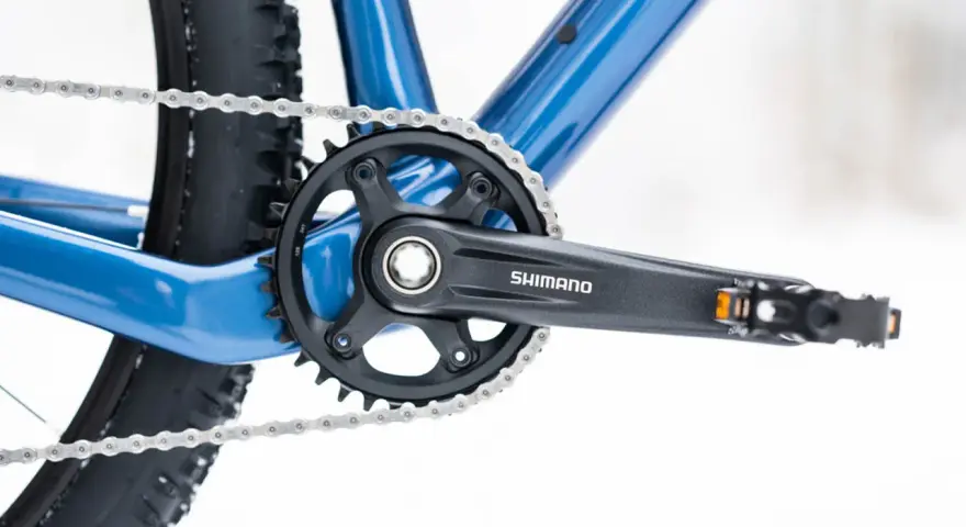 Jak odkręcić pedały w rowerze? Widok na korbę Shimano, łańcuch i fragment ramy roweru.