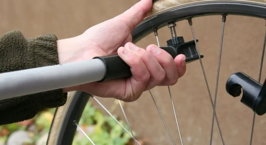 Dłoń trzyma pompkę przy wentylu koła rowerowego 26 cali. Sprawdzanie, jakie ciśnienie w oponach rowerowych 26 cali jest kluczowe dla komfortu jazdy.
