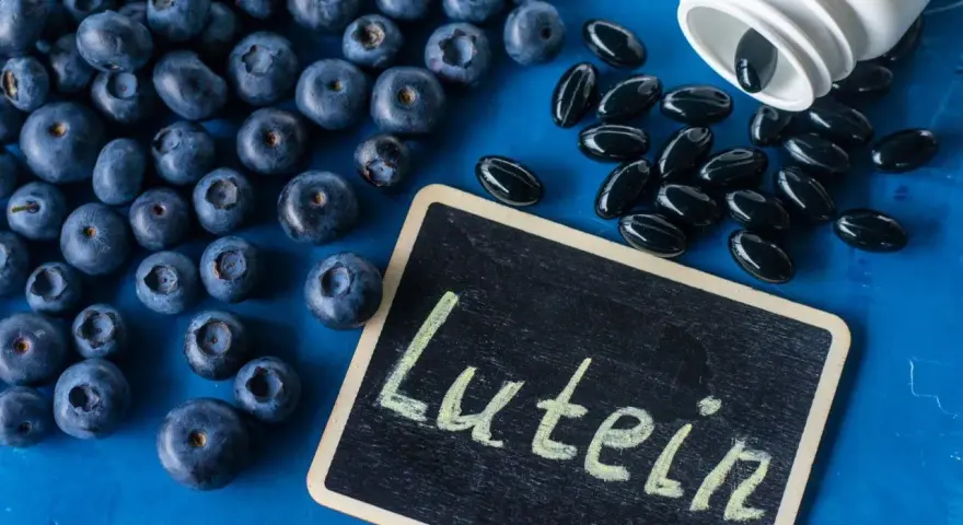 Borówki i kapsułki suplementu diety. Na tabliczce napis "Lutein". Luteina na co? Na zdrowie oczu!