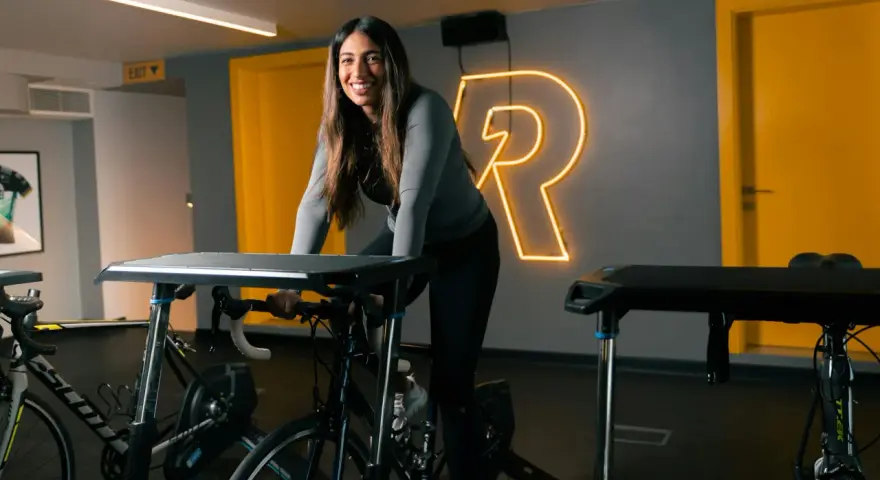 Uśmiechnięta kobieta na rowerze stacjonarnym, gotowa na intensywny trening cardio.