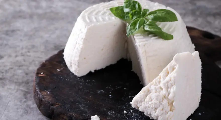 Świeża ricotta z bazylią na ciemnej desce. Idealna do lekkich posiłków, dbając o ricotta kcal.