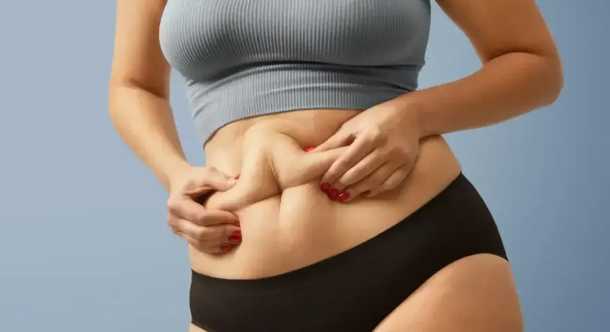 Kobieta z widocznym fałdem tłuszczu na brzuchu, mimo szczupłej sylwetki. Zjawisko "skinny fat" w praktyce.