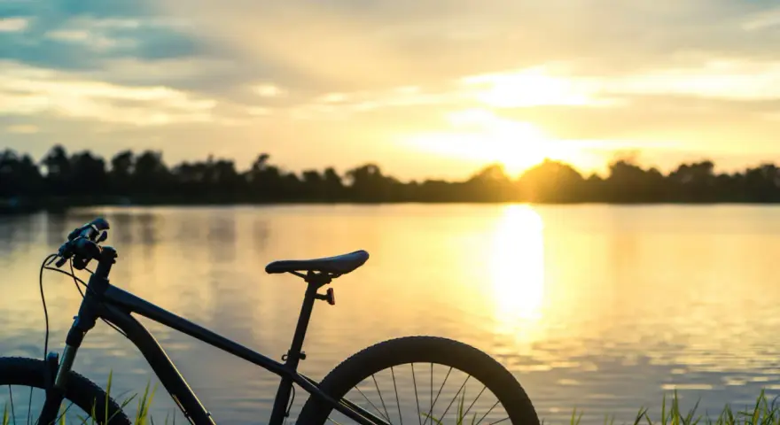 Rower na tle zachodzącego słońca nad jeziorem. Idealne miejsce na odkrywanie tras rowerowych Mazur.