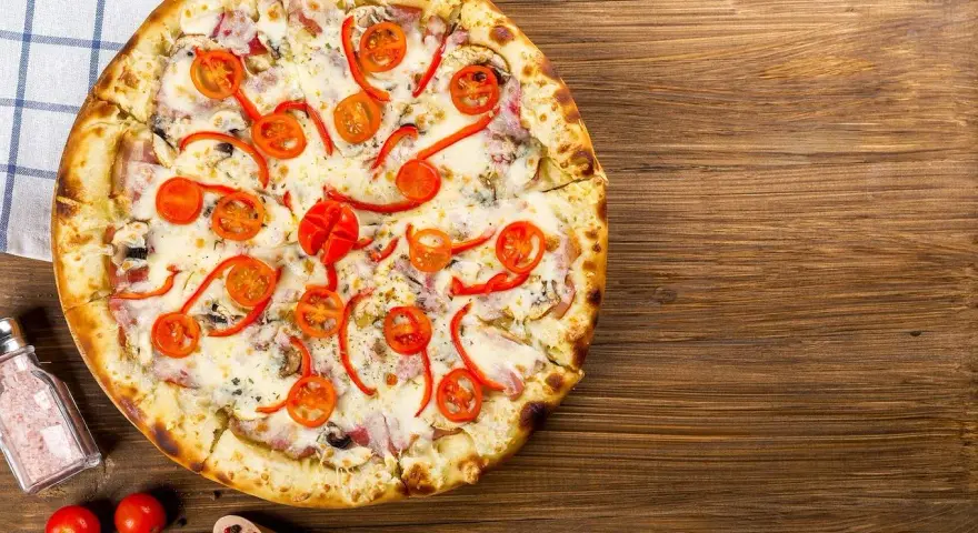 Apetyczna pizza z pomidorkami i papryką, idealna na wieczór. Czy zastanawiałeś się nad pizza hut kalorie?