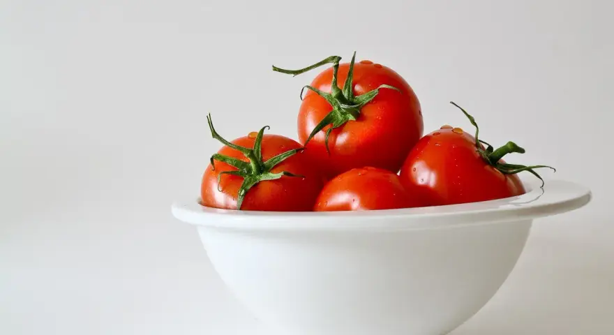 Kilka soczystych pomidorów w białej misce. Niska zawartość pomidor kcal sprawia, że są idealne na zdrową przekąskę.