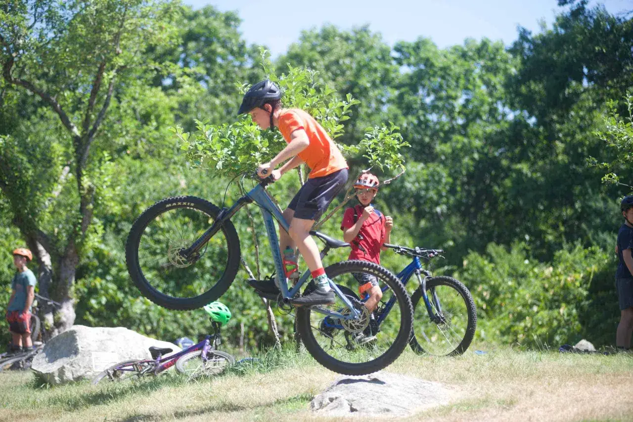 Chłopiec na rowerze MTB wykonuje skok. To świetna zabawa, a rower mtb co to znaczy? To rower górski do jazdy po trudnym terenie.