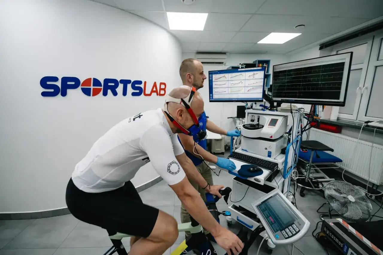 Zawodnik na rowerze stacjonarnym w masce oddechowej, badanie progu mleczanowego w Sports Lab.