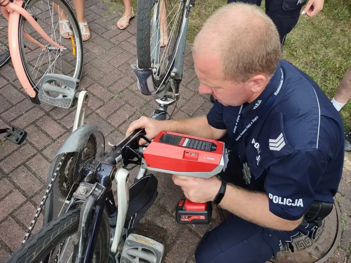 Policjant dokonuje rejestracji roweru za pomocą urządzenia e-mark. Akcja ma na celu zwiększenie bezpieczeństwa i zapobieganie kradzieżom.