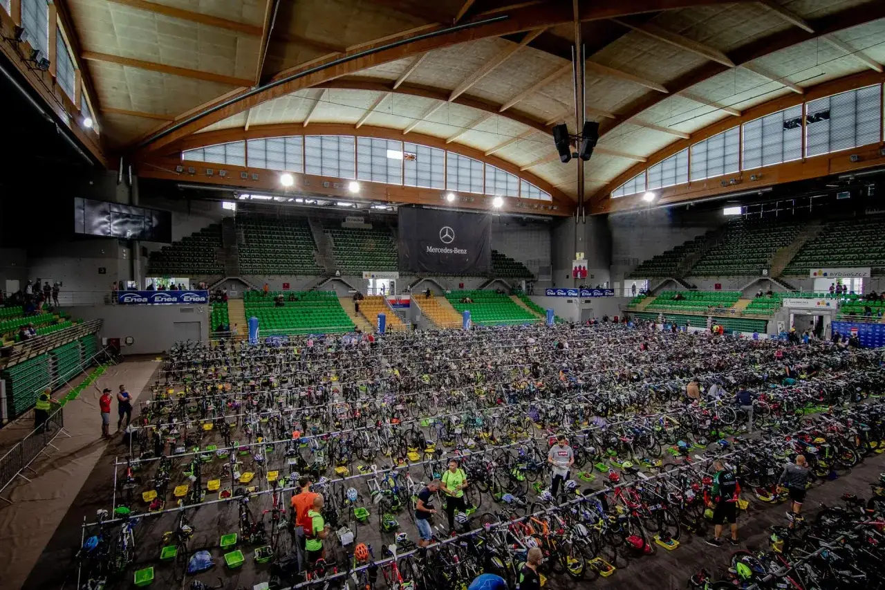 Ogromna hala sportowa wypełniona rowerami czeka na uczestników triathlonu olimpijskiego.