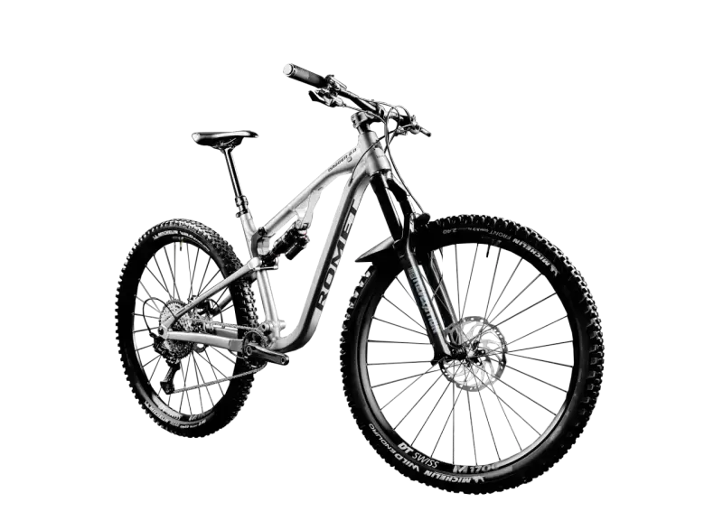 Srebrny rower MTB Romet Dagger 2.0 z pełnym zawieszeniem i oponami Michelin Wild Enduro. To sprzęt do pokonywania trudnych tras.